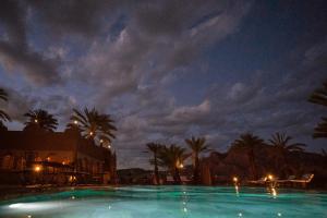 a large swimming pool at night with palm trees at Lodge Hara Oasis in Agdz