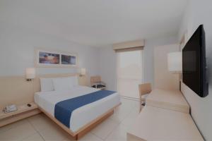 een slaapkamer met een bed en een flatscreen-tv bij City Express by Marriott Minatitlán in Minatitlán