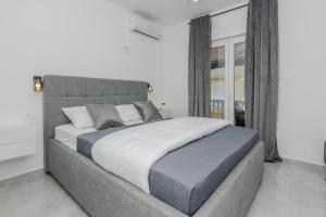 una camera da letto con un grande letto con lenzuola bianche e blu di Apartments Anđelka a Bibinje (Bibigne)