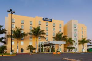 een groot gebouw met palmbomen ervoor bij City Express by Marriott Celaya Parque in Celaya