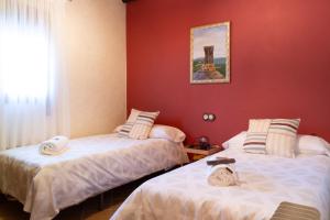 - 2 lits dans une chambre aux murs rouges dans l'établissement El Pinsapo Casa Rural, à Cuevas del Becerro