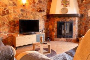 - un salon avec une télévision et un mur en pierre dans l'établissement El Pinsapo Casa Rural, à Cuevas del Becerro