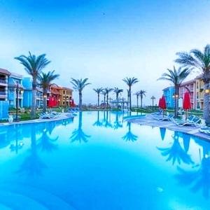 a large swimming pool with palm trees and buildings at Porto matrouh for family in Marsa Matruh