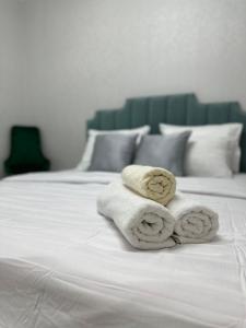 2 serviettes assises au-dessus d'un lit blanc dans l'établissement Отау сити, à Kamennaya Balka