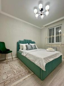- une chambre avec un lit vert et un lustre dans l'établissement Отау сити, à Kamennaya Balka