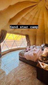 a bedroom with a large bed and a large window at Sand Star Camp in Wadi Rum