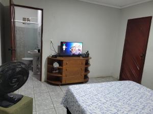 um quarto com uma televisão numa cómoda com uma cama em Quarto - Canto Juazeirense em Juazeiro do Norte
