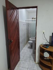 a bathroom with a toilet and a wooden door at Quarto - Canto Juazeirense in Juazeiro do Norte
