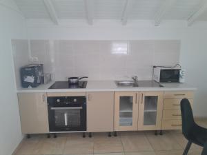 a small kitchen with a sink and a microwave at Séjour au calme in Le Moule