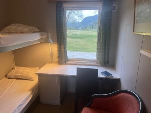 a room with a desk and a bed and a window at Reiårsfossen Hostel & Camping in Bygland