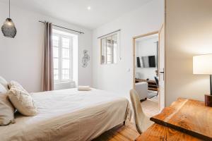 a white bedroom with a bed and a mirror at Cosy appart proche du marché in La Rochelle