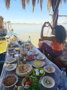 a woman sitting in front of a table full of food at Marassina camp in Siwa