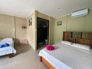 1 dormitorio con 2 camas y una bolsa de color rosa. en Cabinas Travel, en Fortuna