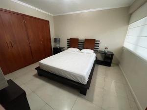 a bedroom with a large bed and wooden cabinets at Suite frente al río en Puerto Santa Ana Riverfront in Guayaquil