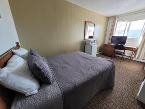um quarto com uma cama e uma secretária com um computador em GRIZZLY MOTEL em Swan Hills