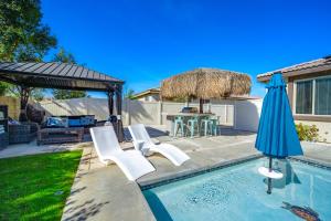 een zwembad met witte stoelen en een parasol bij Millay’s Home Vacation in Indio