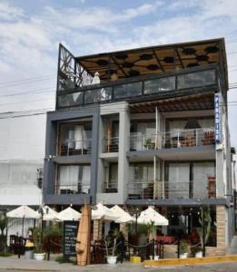 a building with tables and umbrellas in front of it at Huanchaco Paradise Hotel in Huanchaco