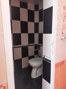 uma casa de banho com um WC e uma parede em xadrez em Tatil evi em Sheki