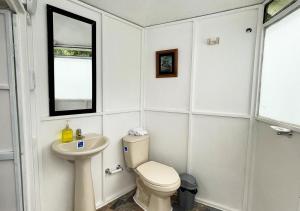 a white bathroom with a toilet and a sink at Yaque Glamping in San Francisco