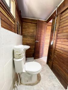 een badkamer met een toilet en een houten muur bij Yaque Glamping in San Francisco