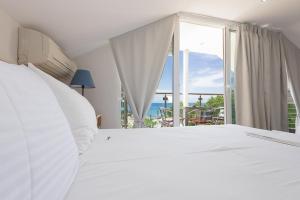 a white bed with a view of the ocean at LE MONDE Seaview Suites in Nea Kalikratia