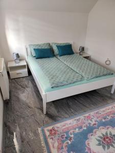 ein Schlafzimmer mit einem Bett mit blauen Kissen und einem Teppich in der Unterkunft Apartment Sofia in Bihać