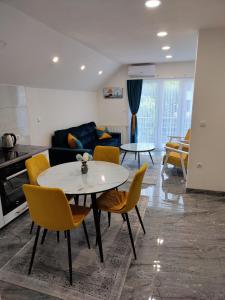 ein Wohnzimmer mit einem weißen Tisch und gelben Stühlen in der Unterkunft Apartment Sofia in Bihać + 15 Fotos