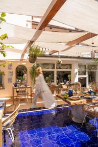 una mujer caminando por un patio con azulejos azules en Maison Fernanda, en SantʼAgata sui Due Golfi