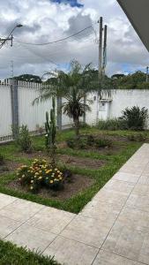 een tuin met een palmboom en bloemen voor een hek bij casa de campo, dentro do urbano. in Piraquara