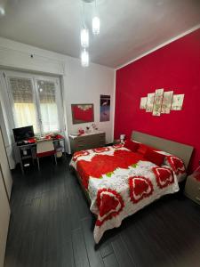 1 dormitorio con pared roja, cama y escritorio en Affittacamere Sa Pardula en Cagliari