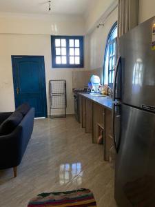 Il comprend une cuisine équipée d'un réfrigérateur en acier inoxydable et une porte bleue. dans l'établissement Dahabiya Studio - Mashraba, à Dahab