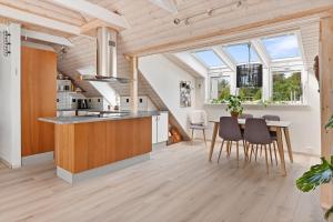 Il comprend une cuisine dotée de plafonds en bois et d'une table avec des chaises. dans l'établissement Leilighet i Nærbø sentrum, à Narbø