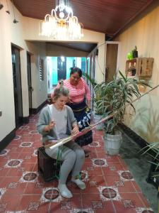 two women are sitting on a brick floor at Hostal Sanjuanerita in San Juan La Laguna