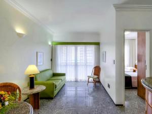 a living room with a green couch and a bed at Premium Flats - Tulip Inn in Fortaleza