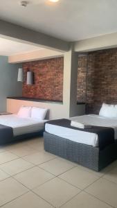 a room with two beds and a brick wall at Hotel BLVD in Playa del Carmen