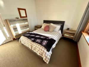 a bedroom with a bed with a blanket and a window at Dog-friendly in Waterloo in Lower Hutt
