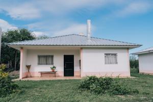 ein kleines weißes Haus mit einer schwarzen Tür und einer Bank in der Unterkunft Las Moras Del Manantial in Termas de Río Hondo
