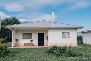 a small white house with a black door and a bench at Las Moras Del Manantial in Termas de Río Hondo