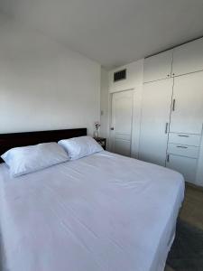 una camera da letto con un grande letto bianco e armadi bianchi di Apartamento céntrico en porlamar a Porlamar
