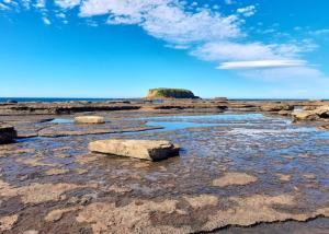 una playa rocosa con dos rocas en el agua en North Durras Beach Cottage, en Durras