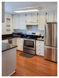 una cocina con armarios blancos y electrodomésticos de acero inoxidable en Haven Place en Alexandria