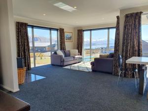 a living room with couches and a table and windows at Southholm in Lake Tekapo