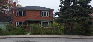 a red brick house with a fence in front of it at High Park Single room with exclusive washroom and kitchen for solo travelers in Toronto