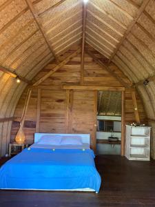 ein blaues Bett in einem Zimmer mit Holzdecke in der Unterkunft Hakiki Inn Bungalows in Tetebatu