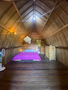 ein Schlafzimmer mit einem lila Bett in einem Holzzimmer in der Unterkunft Hakiki Inn Bungalows in Tetebatu