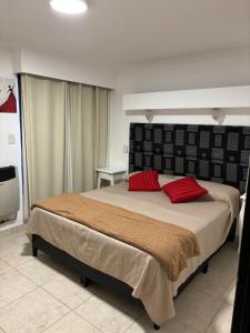um quarto com uma cama grande e almofadas vermelhas em Robinson Apartamentos SOLO FAMILIAS em Villa Carlos Paz