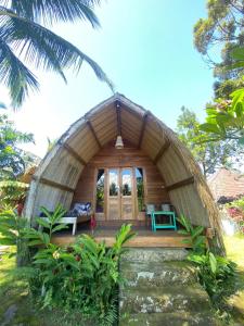 ein rundes Haus mit einer Veranda im Wald in der Unterkunft Hakiki Inn Bungalows in Tetebatu