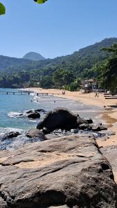 a beach with rocks and people swimming in the water at Suítes Encanto do Pai in Praia de Araçatiba