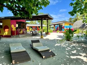 - une terrasse avec 2 chaises longues et un bâtiment dans l'établissement Rangiroa Cottage, à Avatoru