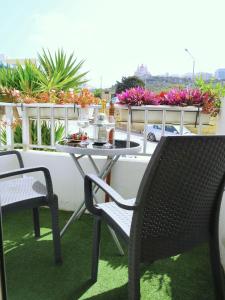 uma mesa e cadeiras numa varanda com flores em 3 Balconies South Views Special Bedroom 5 mins to beach em Mellieħa